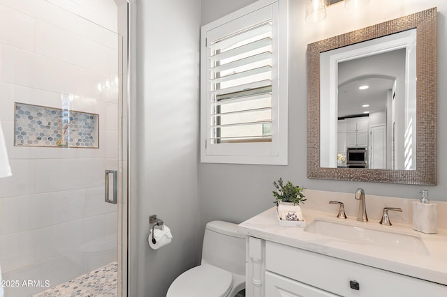 bathroom with vanity, toilet, and a shower with shower door