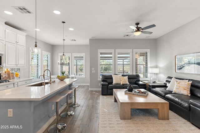 living room with ceiling fan, sink, and light wood-type flooring