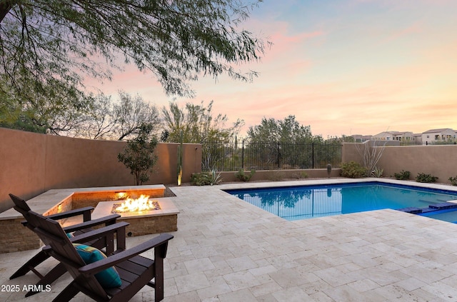 pool at dusk featuring a patio area and an outdoor fire pit