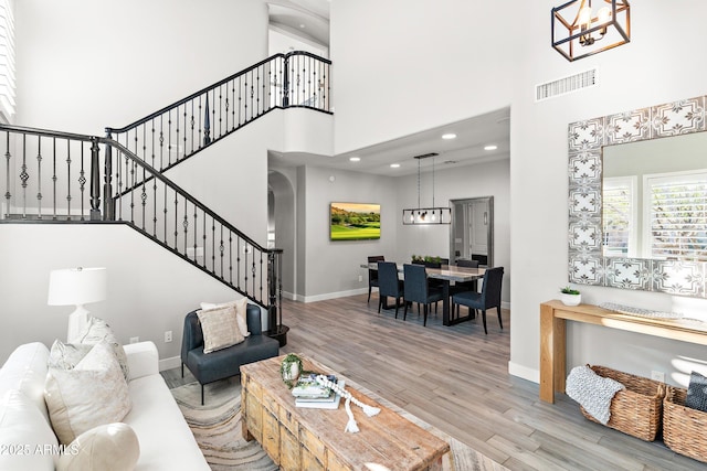 living room featuring a notable chandelier, a high ceiling, and light wood-type flooring