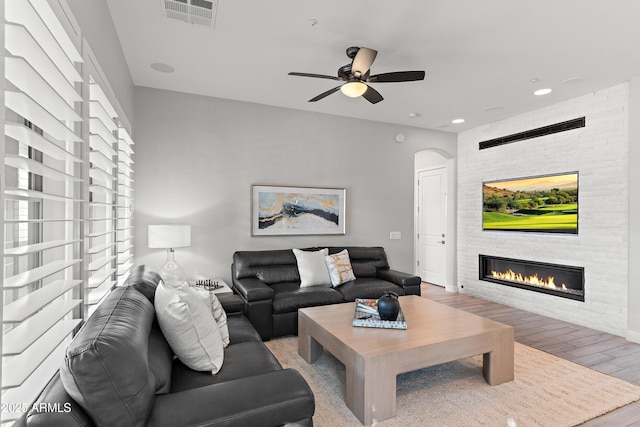 living room featuring a fireplace, light hardwood / wood-style floors, and ceiling fan