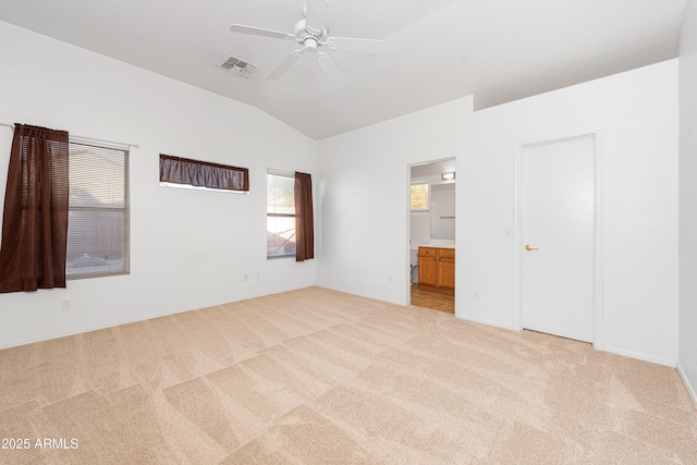 unfurnished bedroom with light carpet, visible vents, connected bathroom, ceiling fan, and vaulted ceiling