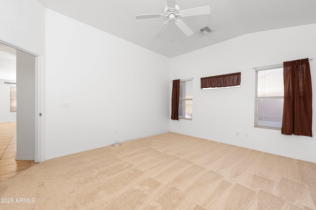 spare room with light carpet, plenty of natural light, lofted ceiling, and visible vents