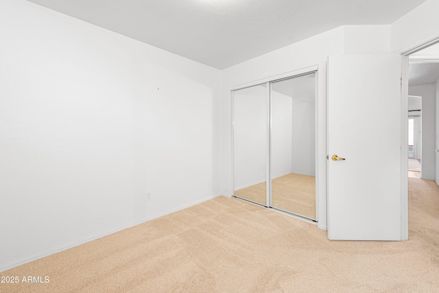 unfurnished bedroom with a closet and light colored carpet