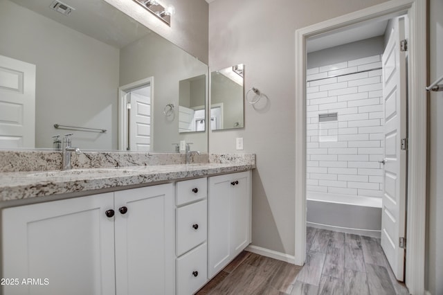 bathroom featuring vanity, tiled shower / bath combo, and hardwood / wood-style floors