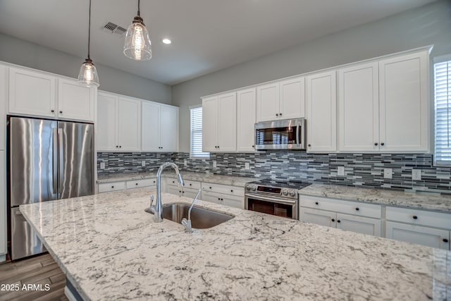 kitchen with stainless steel appliances, white cabinets, hanging light fixtures, and sink