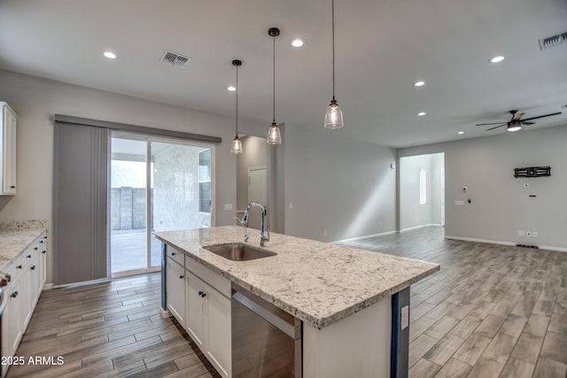 kitchen with a center island with sink, ceiling fan, dishwasher, white cabinets, and sink