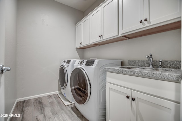 washroom featuring cabinets, washer and clothes dryer, light hardwood / wood-style flooring, and sink