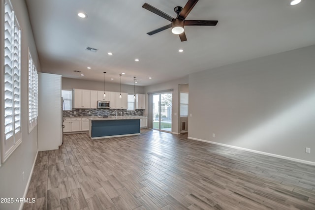 unfurnished living room featuring ceiling fan and light wood-type flooring