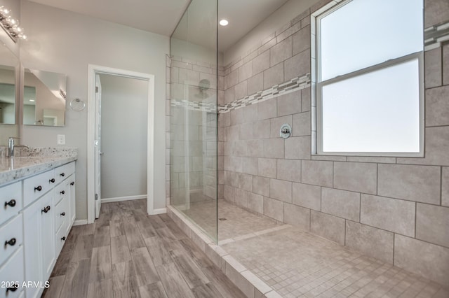 bathroom featuring vanity, wood-type flooring, and tiled shower