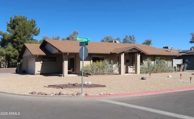 ranch-style home with brick siding, driveway, an attached garage, and roof with shingles