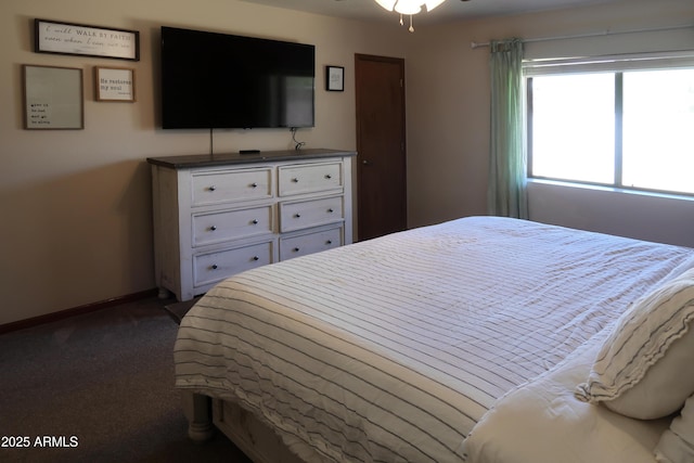 bedroom with dark carpet and baseboards