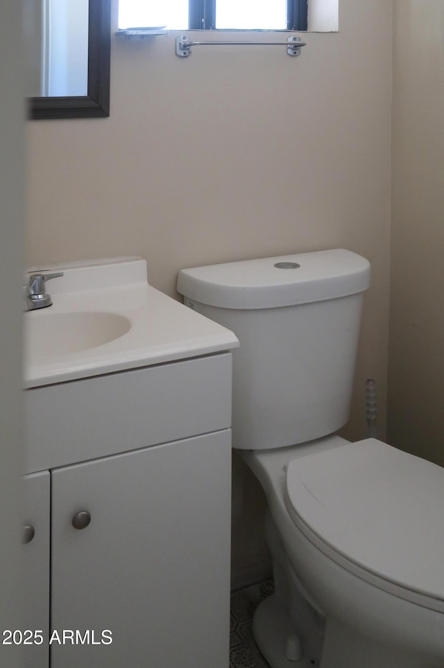 half bath featuring a healthy amount of sunlight, vanity, and toilet