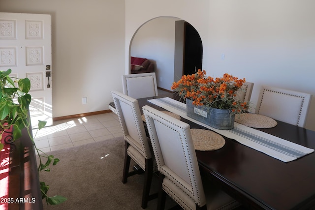 dining area with light tile patterned floors, baseboards, and arched walkways