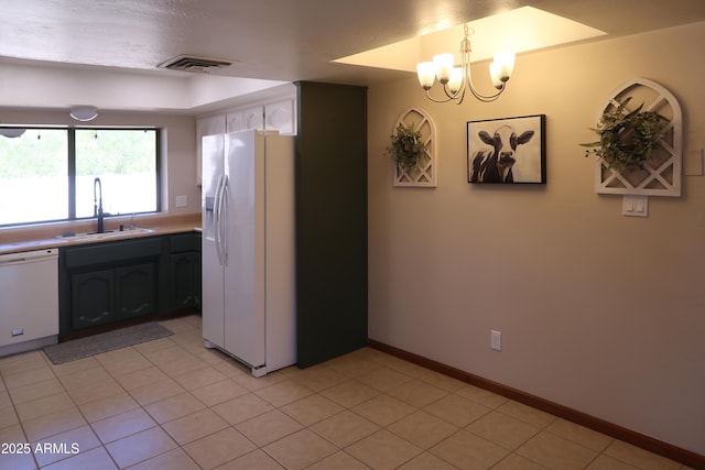 kitchen featuring decorative light fixtures, light countertops, visible vents, a sink, and white appliances