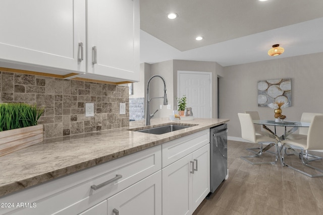 kitchen featuring light stone counters, stainless steel dishwasher, sink, and white cabinets