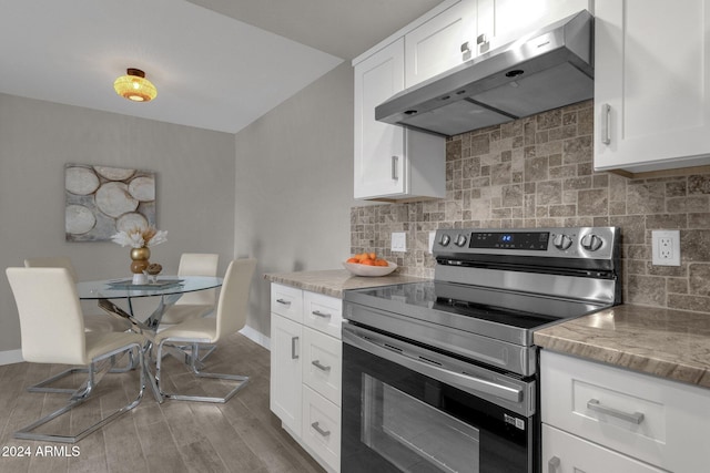 kitchen with white cabinetry, extractor fan, light stone countertops, and stainless steel range with electric stovetop