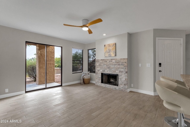 living room featuring a fireplace, light hardwood / wood-style floors, and ceiling fan