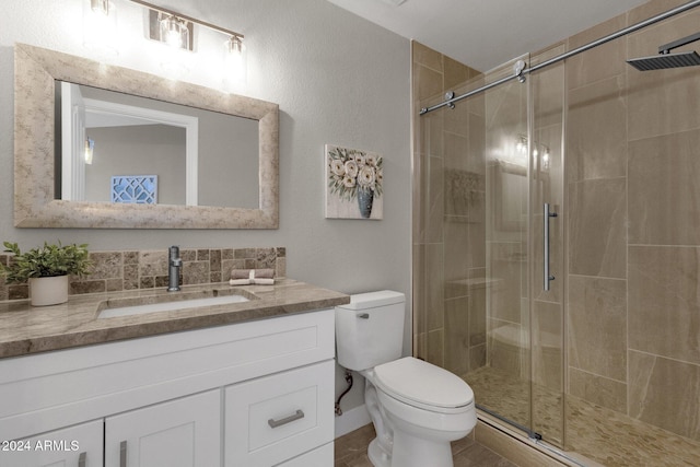 bathroom featuring vanity, toilet, and a shower with door