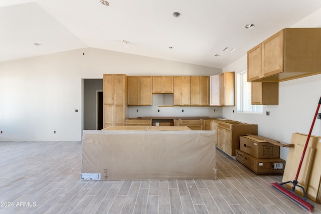 kitchen with vaulted ceiling, a kitchen island, and light brown cabinets