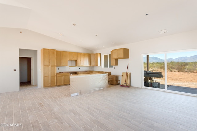 kitchen featuring a mountain view, light brown cabinets, lofted ceiling, and light wood-type flooring