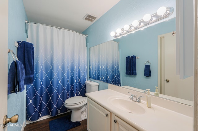 bathroom with visible vents, a shower with shower curtain, toilet, vanity, and wood finished floors