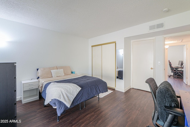 bedroom with a textured ceiling, a closet, visible vents, and wood finished floors