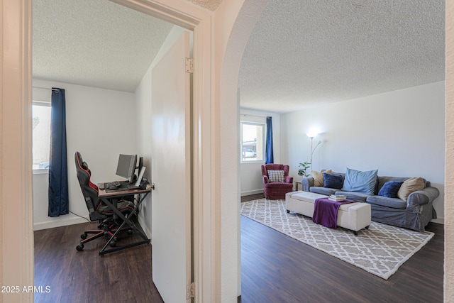 office area featuring arched walkways, a textured ceiling, and wood finished floors