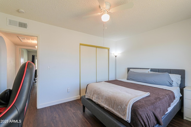 bedroom featuring a closet, visible vents, ceiling fan, a textured ceiling, and wood finished floors