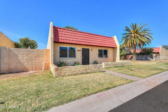 view of front of property featuring a front lawn, a tile roof, and stucco siding