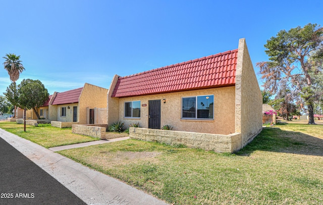 view of front of home with a front yard, a tiled roof, and stucco siding