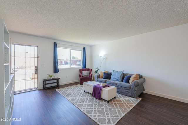 living room featuring a textured ceiling, baseboards, and wood finished floors