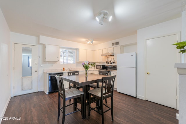 kitchen featuring black dishwasher, dark wood-style flooring, visible vents, freestanding refrigerator, and range