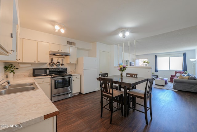 kitchen with visible vents, freestanding refrigerator, stainless steel range with electric stovetop, black microwave, and under cabinet range hood