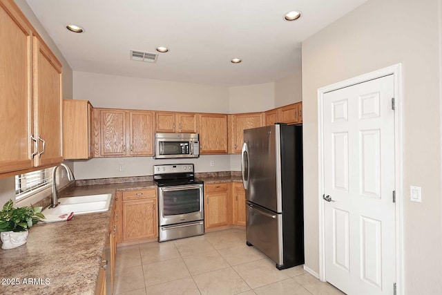 kitchen featuring stone counters, stainless steel appliances, sink, and light tile patterned floors