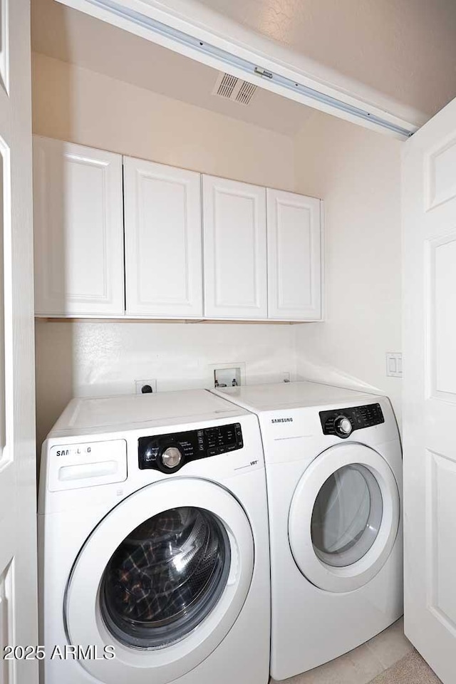 laundry room with washing machine and dryer and cabinets