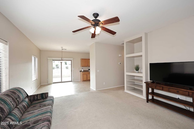 living room featuring built in shelves, ceiling fan, and light carpet