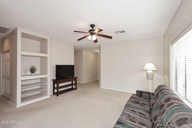 living room featuring light colored carpet, ceiling fan, and built in shelves