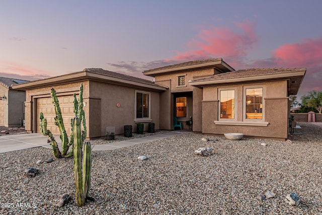 view of front facade featuring stucco siding, an attached garage, a tile roof, and driveway