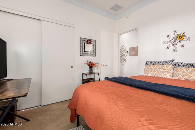 carpeted bedroom with visible vents, a closet, and ornamental molding