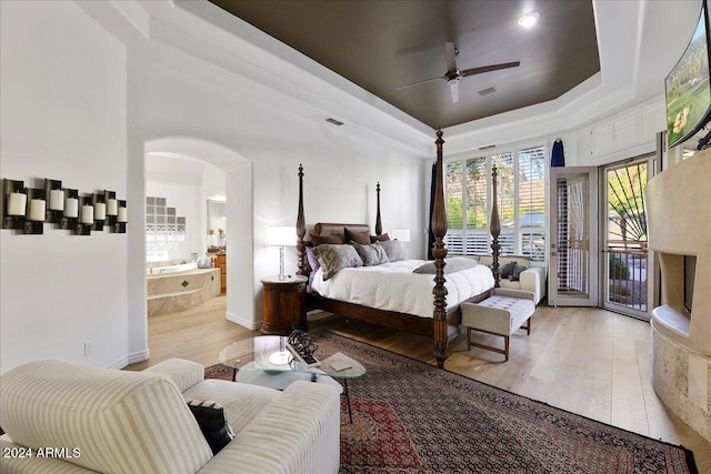 bedroom featuring access to exterior, light hardwood / wood-style floors, a raised ceiling, and ceiling fan