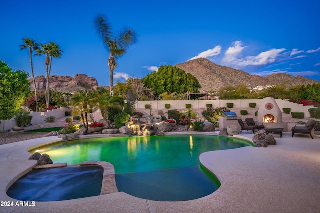 view of pool featuring a mountain view, exterior fireplace, and a patio area