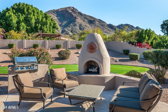 view of patio / terrace with area for grilling, exterior fireplace, and a mountain view