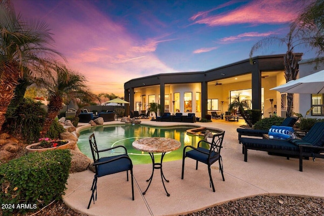 pool at dusk featuring an outdoor hangout area, a patio, and ceiling fan