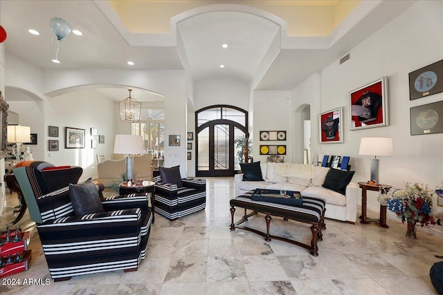 living room featuring a high ceiling, a chandelier, and french doors