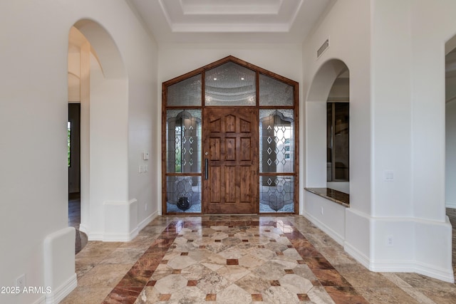 foyer entrance with visible vents, baseboards, and arched walkways