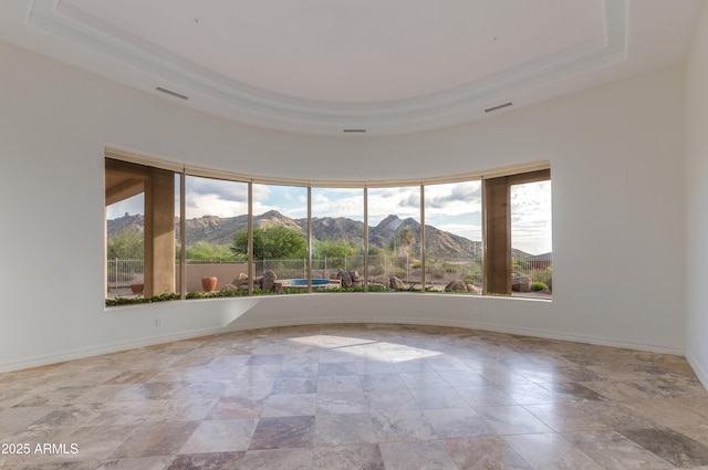 unfurnished room featuring plenty of natural light, a mountain view, and a tray ceiling