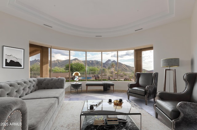 living area featuring a raised ceiling, a healthy amount of sunlight, a mountain view, and visible vents