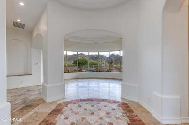 interior space featuring arched walkways, a mountain view, recessed lighting, visible vents, and baseboards