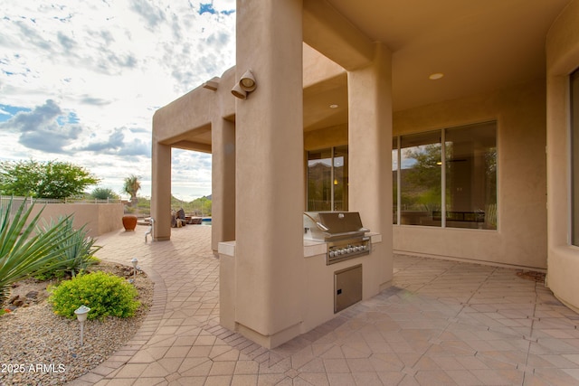 view of patio / terrace with exterior kitchen, a grill, and fence